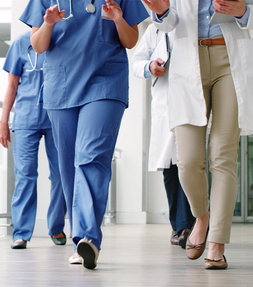 medical professionals in scrubs and white jackets walking, faces not pictured