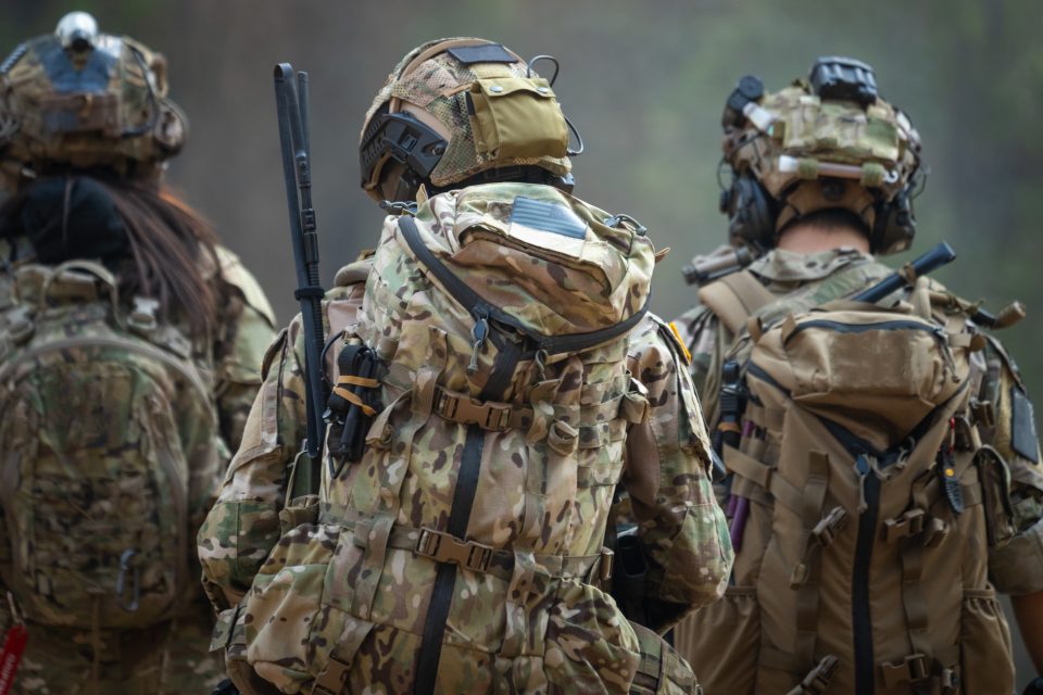 Backside of Three Soldiers Wearing Full Gear and Walking Together Outside