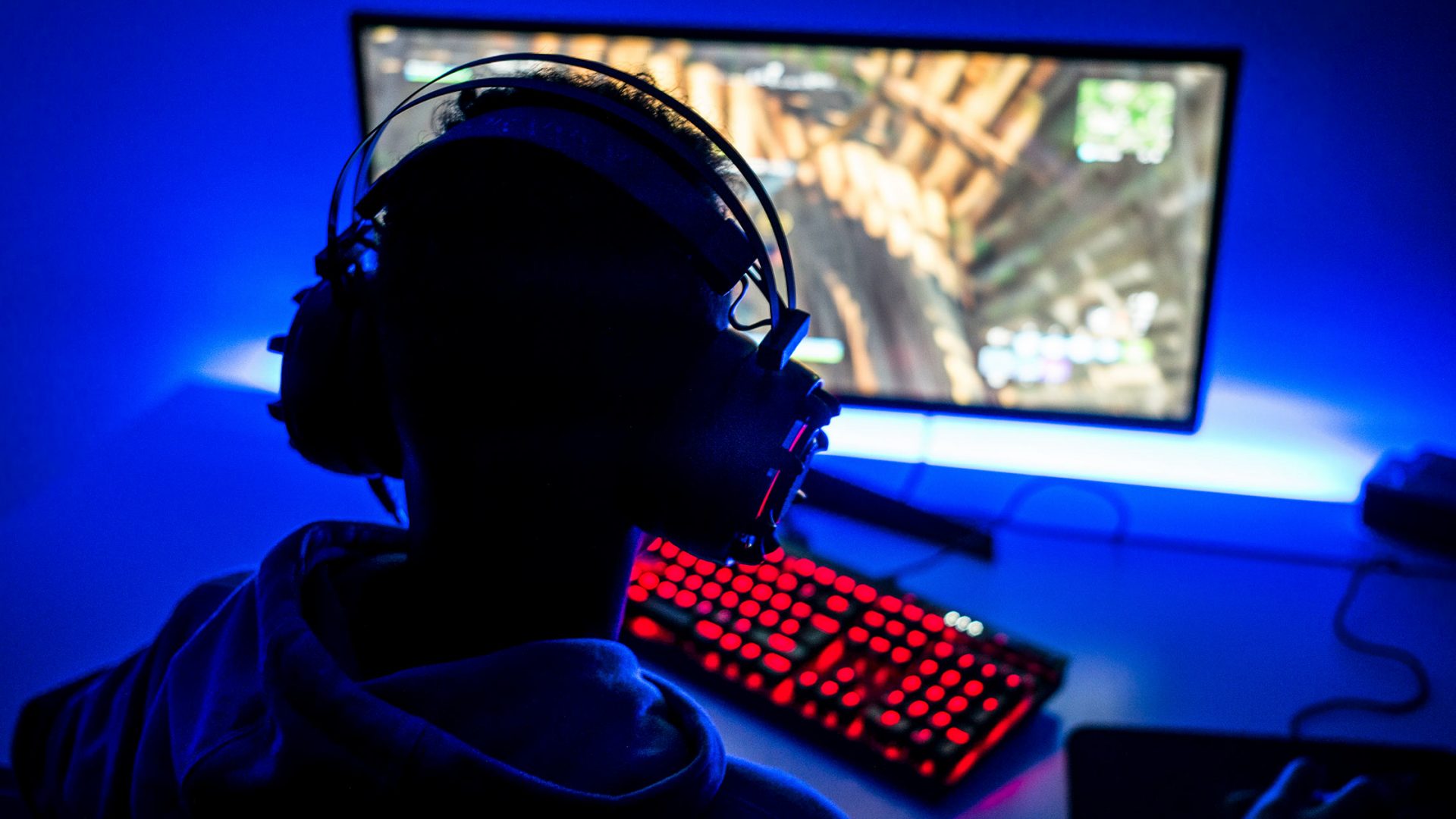 Person Wearing Headphones and Playing Game on Computer