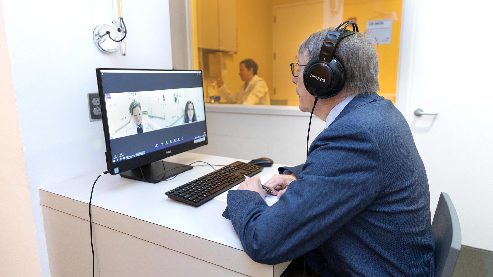 Dr. Neil Busis sits at a computer watching a mock teleneurology appointment as a doctor interacts with a standardized patient